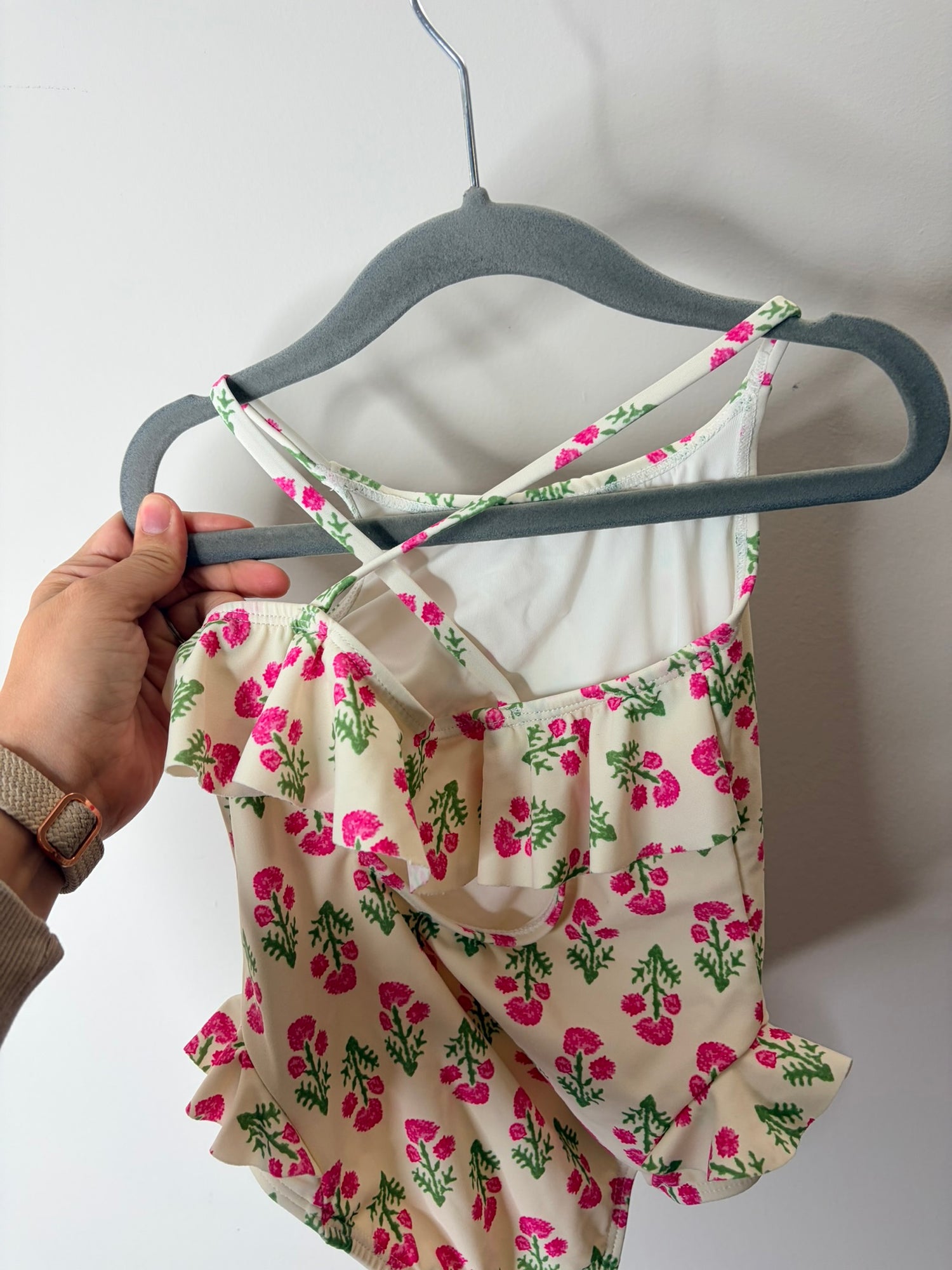 Pink floral swim cover-up and matching swimsuit set with green floral accents on hangers.