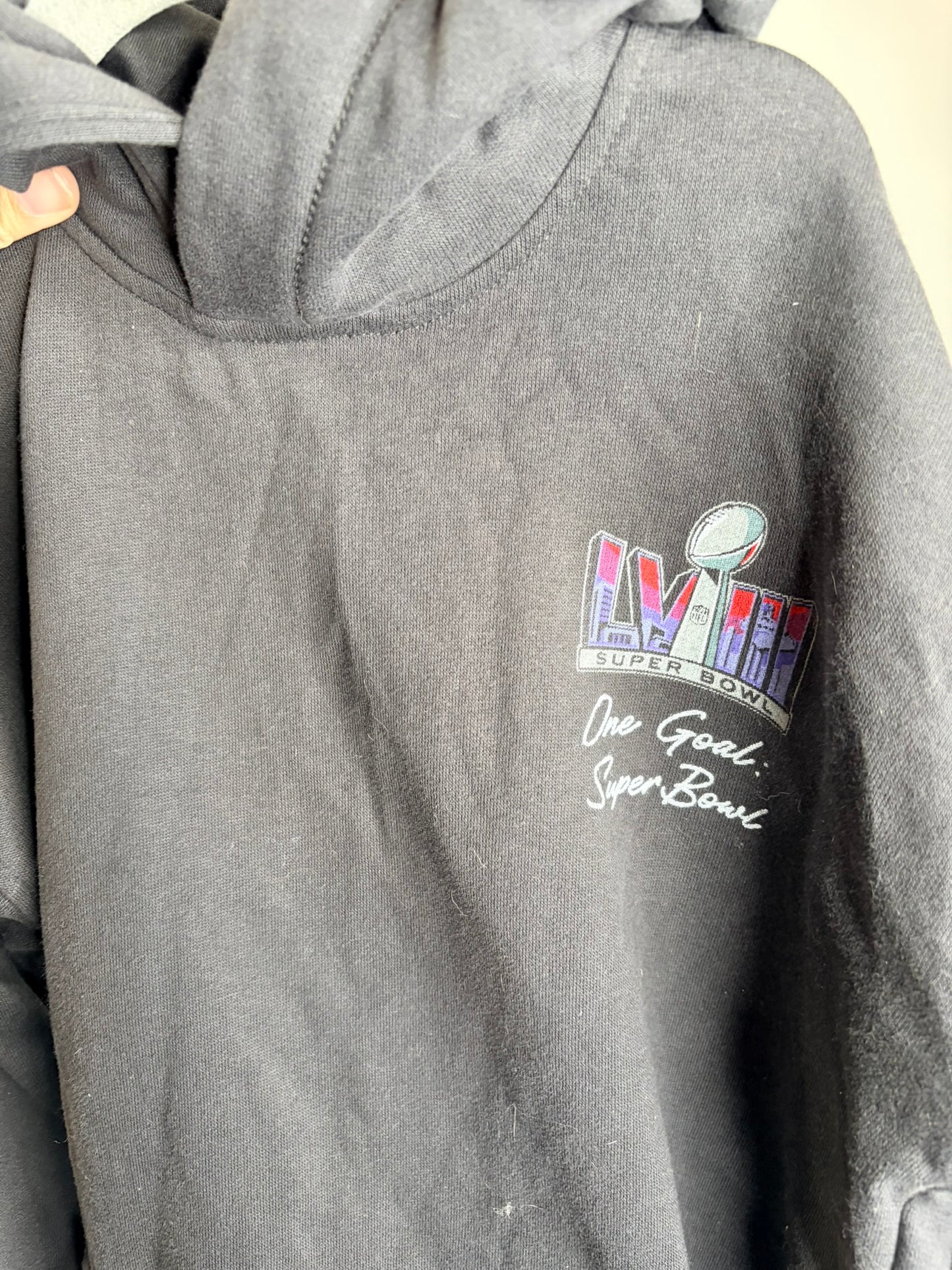 Black NFL hoodie featuring Road to the Super Bowl graphic with football and stadium design on the back.