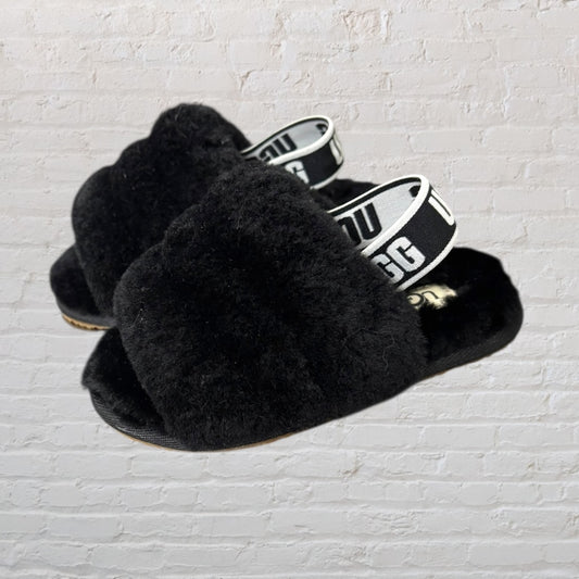 Black fluffy open-toe UGG slippers featuring an elastic logo strap.
