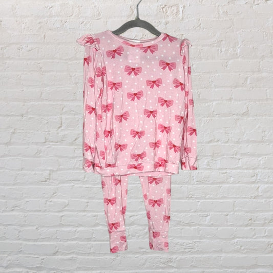 Pink pajama set with red bow patterns and white polka dots, featuring long sleeves and pants.