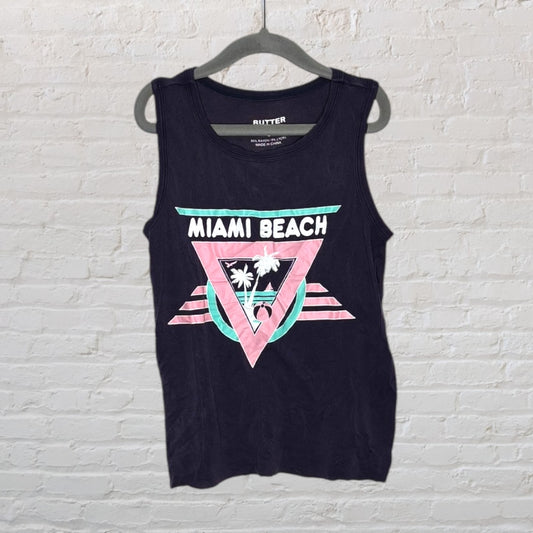 A black tank top with a colorful Miami Beach graphic featuring a pink and green design, displayed on a hanger.