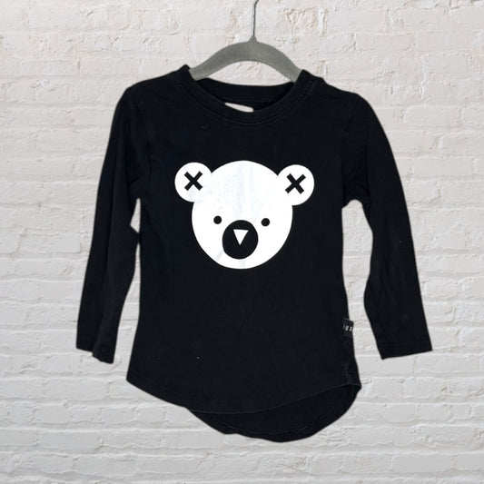 Black long sleeve shirt with a white graphic bear face and cross eyes design on the front, hanging on a hanger.