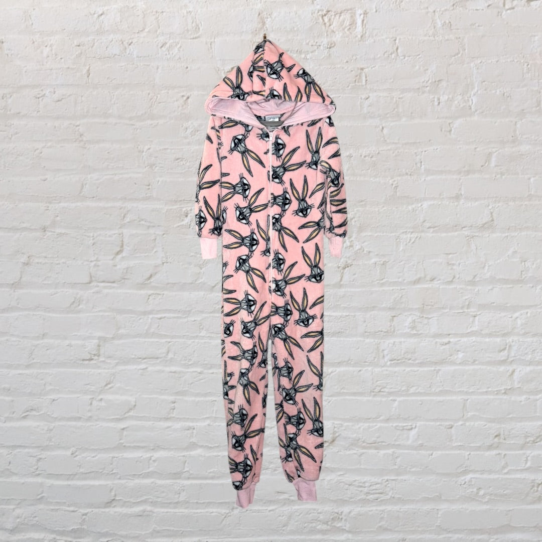 Pink onesie with Bugs Bunny graphic print and hood, hanging against a brick wall.
