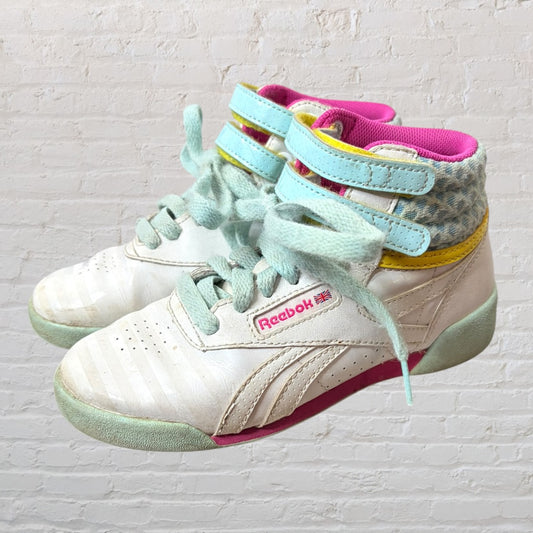 Reebok high-top sneakers in white with colorful accents in pink, blue, and yellow, featuring Velcro straps and laces.