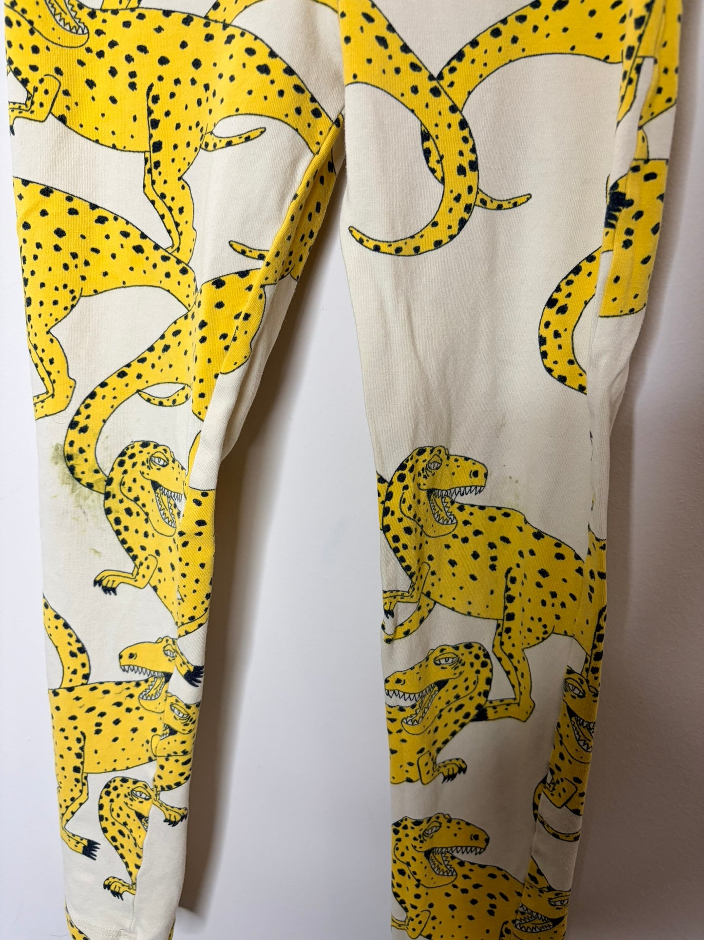 Yellow leggings with black leopard print, hanging against a white brick background.