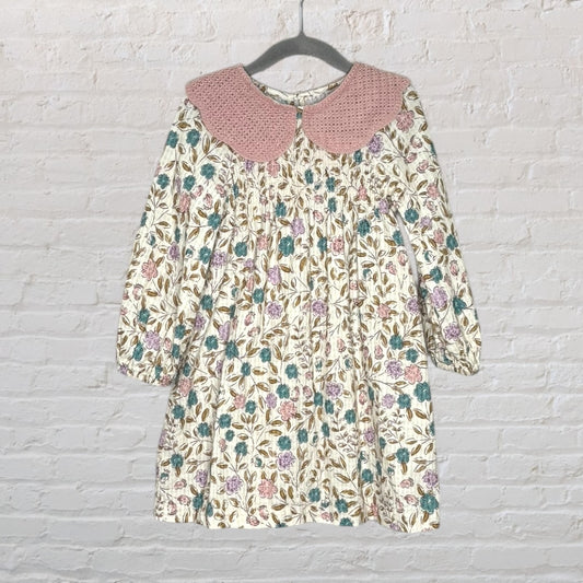 A long-sleeve floral dress featuring a pink crochet collar and multicoloured flowers on a cream background.