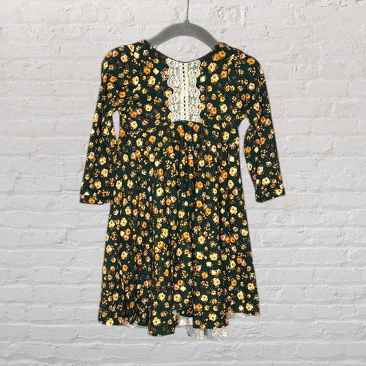Dark green long sleeve dress with yellow floral print and white lace detail on the chest, hanging on a hanger.