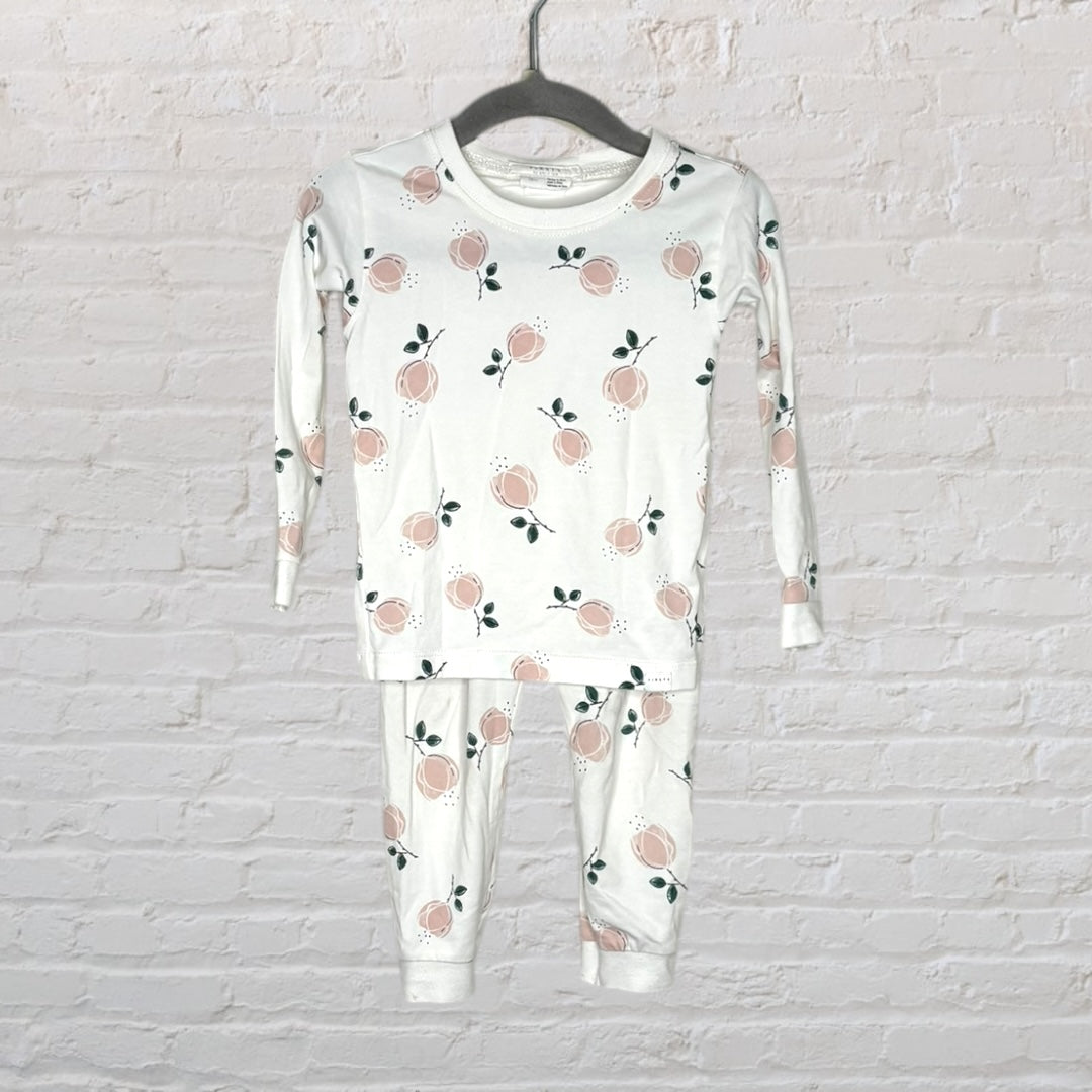 White pajama set with peach and green leaf patterns, featuring a top and bottom hanging on a gray hanger.