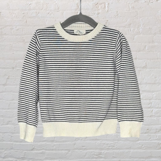 A black and white striped knit sweater with ribbed cuffs and neckline, hanging on a black hanger.