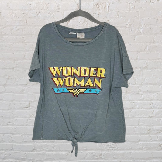 Gray Wonder Woman T-Shirt with knot front and colorful logo print, hanging on a hanger.