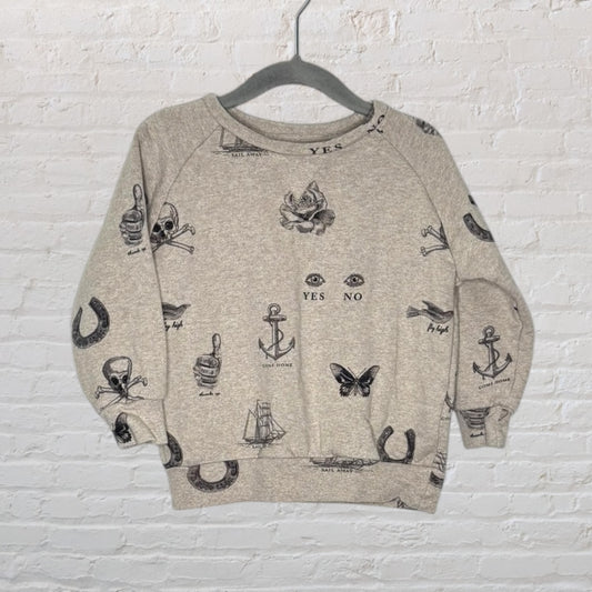 Heather grey sweatshirt with tattoo-inspired graphics including anchors, skulls, and horseshoes, hanging on a hanger.
