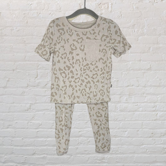 A beige and light brown leopard print pajama set featuring a short-sleeve top with a pocket and matching pants, hanging on a dark hanger.
