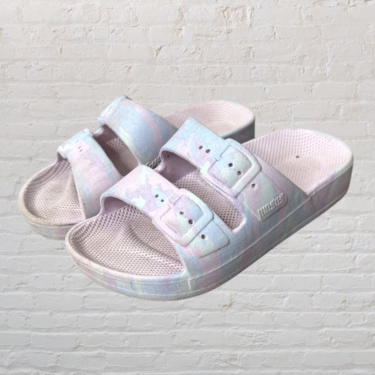 Mixcder pastel tie-dye slide sandals with double buckles set against a brick background.