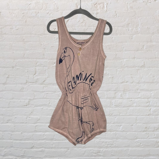 Beige sleeveless romper with a flamingo graphic and button detailing at the top, hanging on a black hanger.