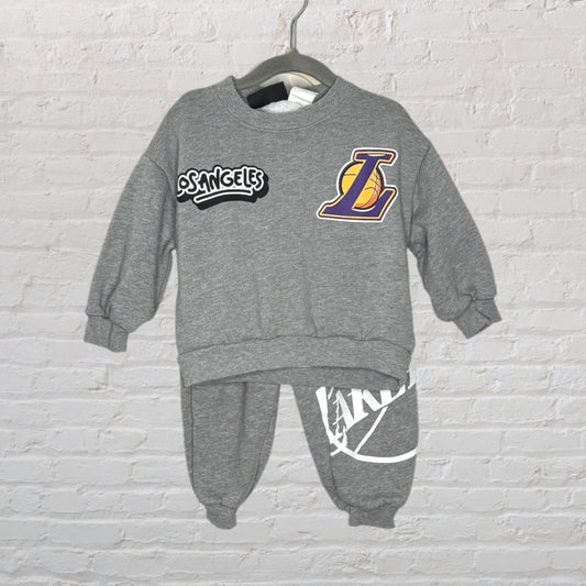 Grey Los Angeles Lakers sweatshirt and pants set with team logos displayed on a hanger.