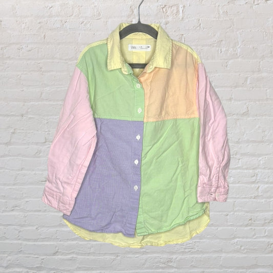 Colorful pastel patchwork button-up shirt with long sleeves and a collar, hanging on a hanger.