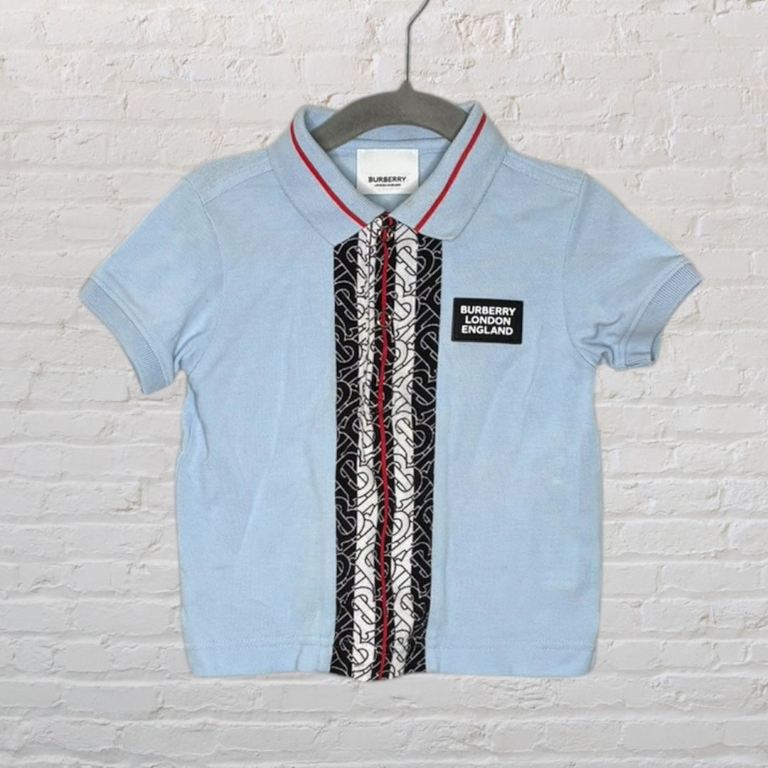 Light blue Burberry London polo shirt with black and white pattern strip and brand logo on the front.