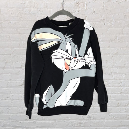 Black sweatshirt with large Bugs Bunny graphic, displayed on a hanger against a white brick wall.