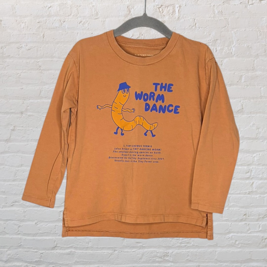 Orange long sleeve shirt featuring a dancing worm graphic and 'The Worm Dance' text by Tinycottons.