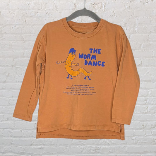 Orange long sleeve shirt featuring a dancing worm graphic and 'The Worm Dance' text by Tinycottons.
