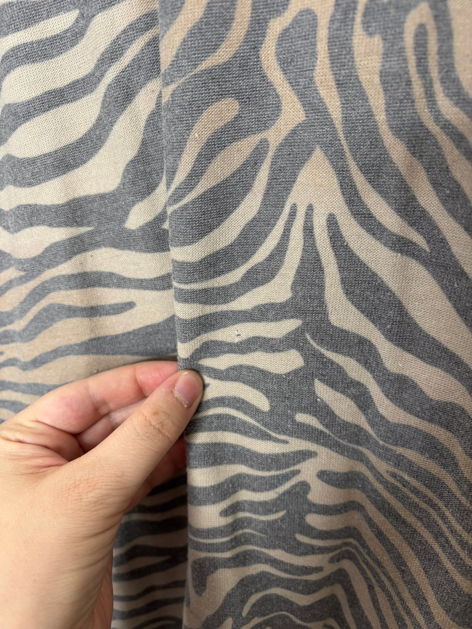 Women's zebra print t-shirt dress in beige and black, with short sleeves and a relaxed fit, hanging on a black hanger.