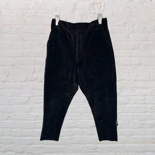 Black velvet cropped pants hanging against a white brick wall.