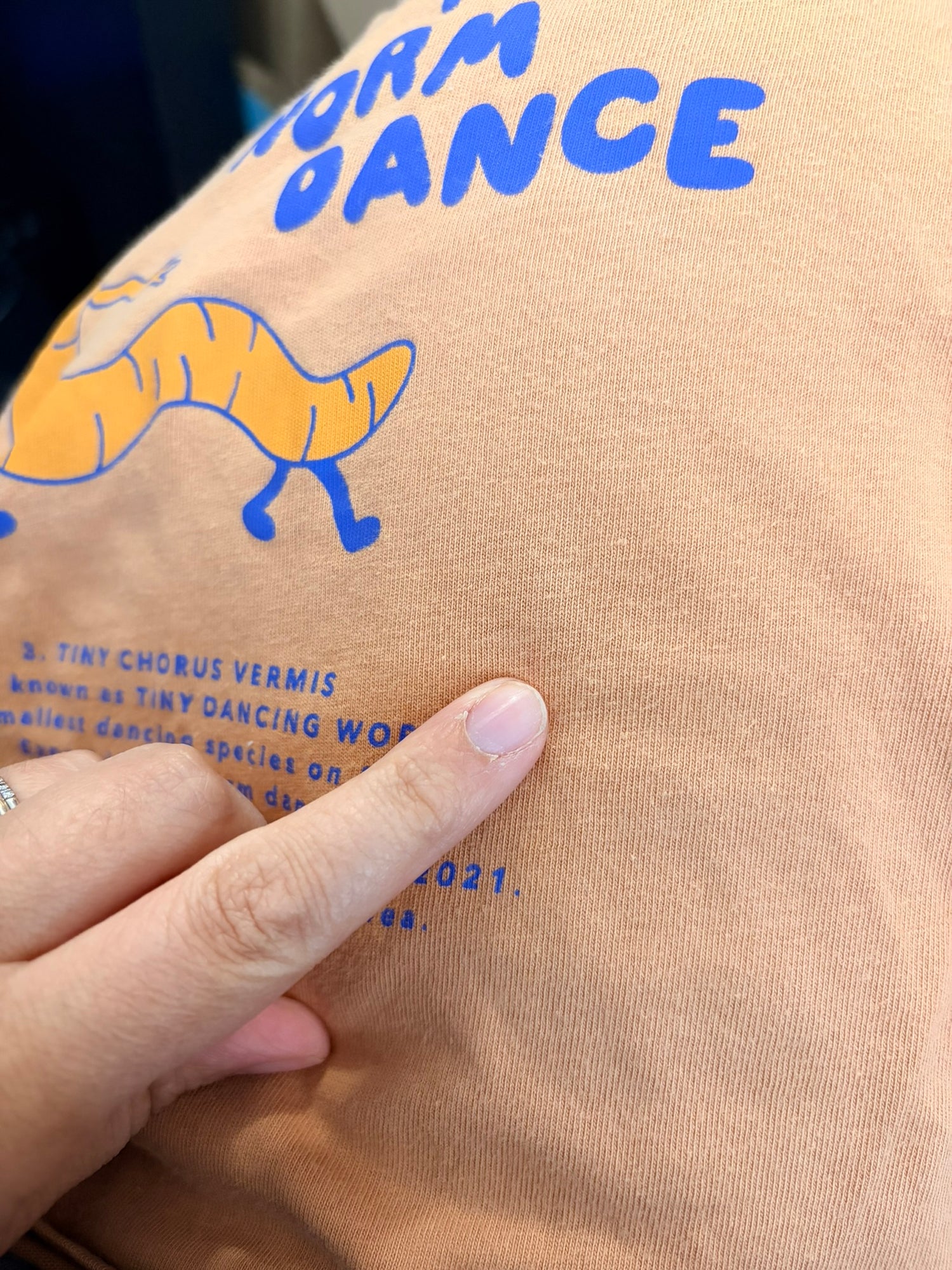 Orange long sleeve shirt featuring a dancing worm graphic and 'The Worm Dance' text by Tinycottons.