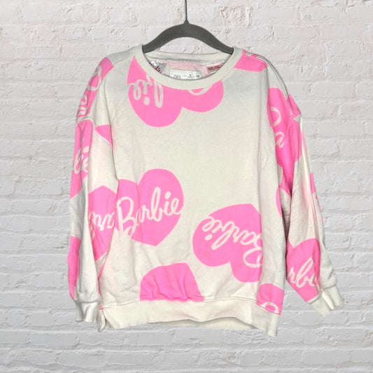 White and pink Barbie sweatshirt with heart logos and text, hanging on a black hanger.