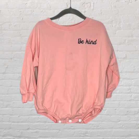 Pink baby onesie with 'Be kind' embroidered on the chest, featuring snap closures at the bottom.