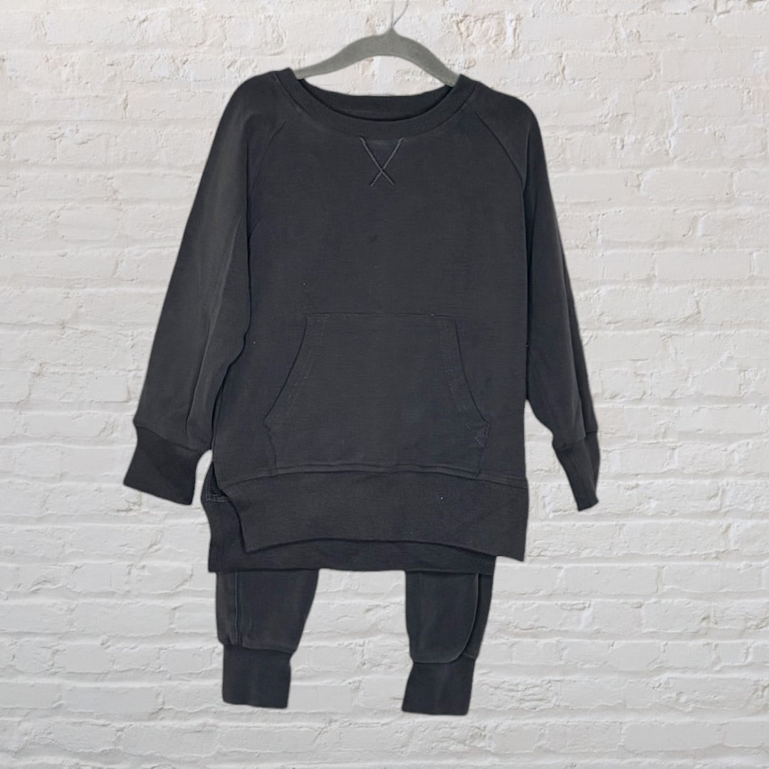 Black lounge set with a long-sleeve top featuring a front pocket and matching pants hanging on a hanger.