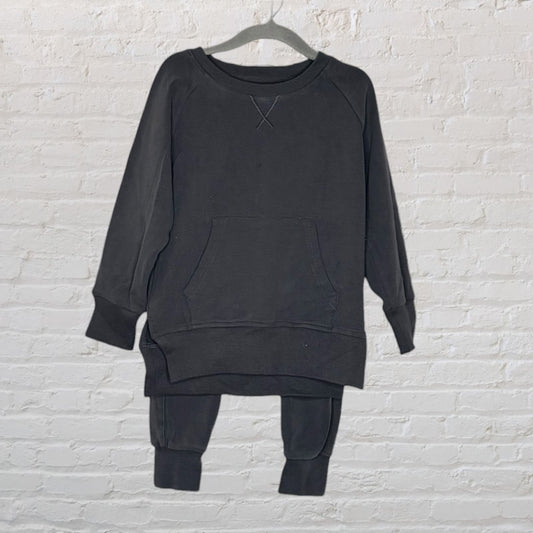 Black lounge set with a long-sleeve top featuring a front pocket and matching pants hanging on a hanger.