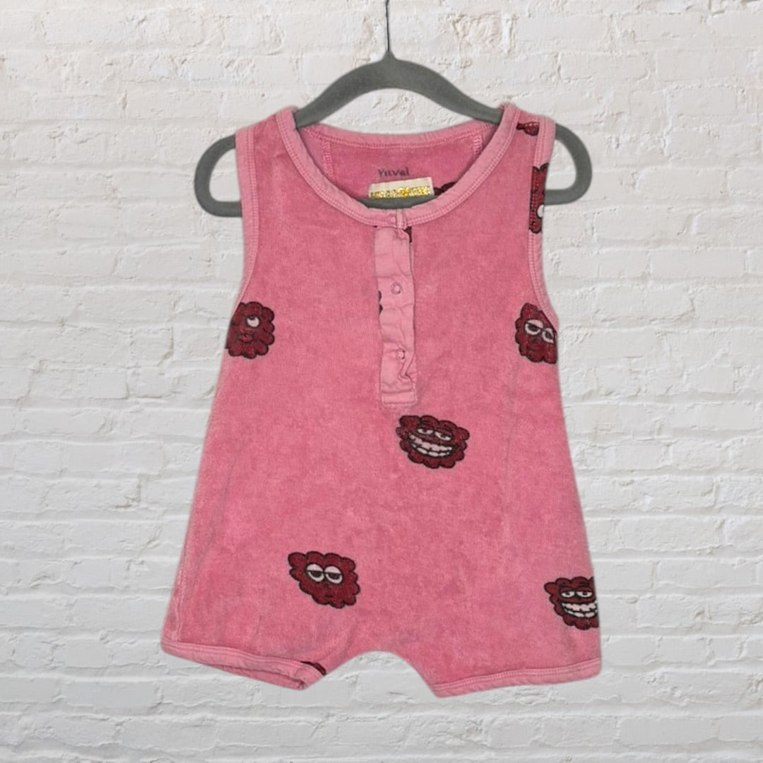 Pink sleeveless romper with button closure and playful printed motifs, hanging on a hanger.