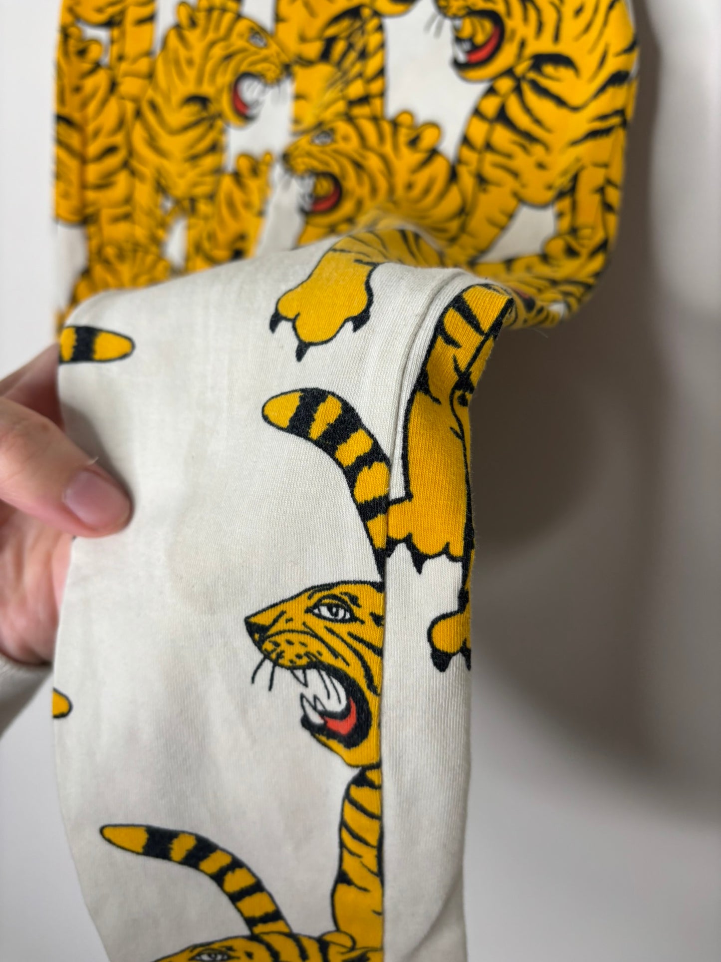 Vibrant leggings with all-over tiger print in yellow and black, hanging against a white brick wall.