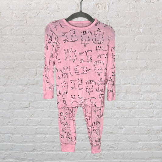 Pink pajama set with black cartoon cat prints, including a long-sleeved top and pants, hanging on a hanger.