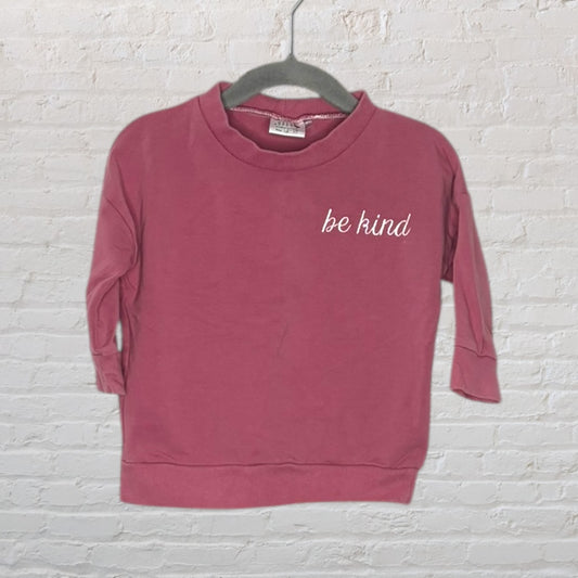Dusty rose sweatshirt with 'be kind' text on the chest, hung on a hanger.