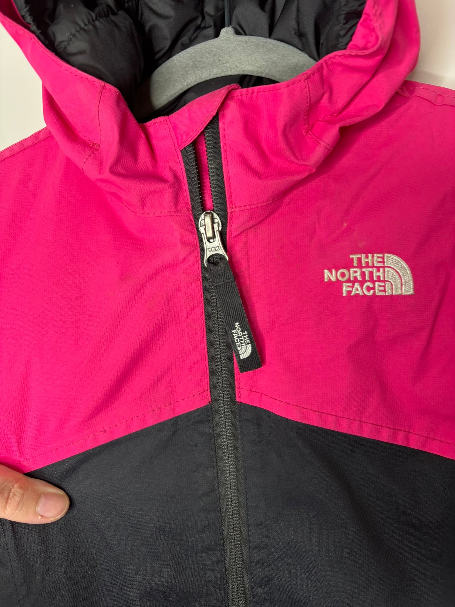 Pink and black hooded jacket by The North Face, designed for unisex wear, featuring a full zip and logo on the chest.