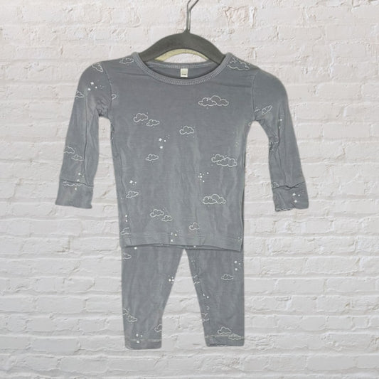 Gray long sleeve pajama set with cloud and star patterns hanging on a black hanger against a brick wall.