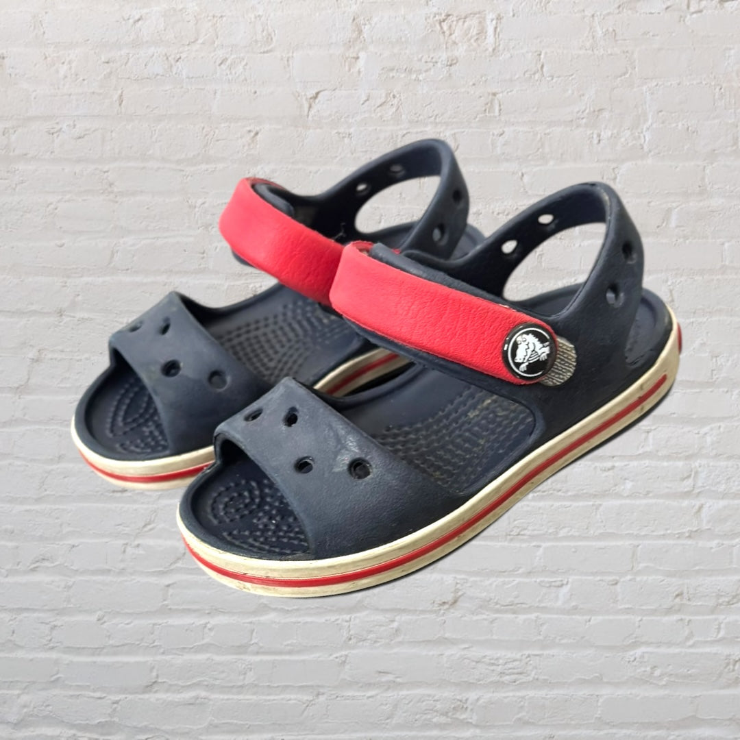 Navy blue kids sandals with red straps, featuring a sporty design and perforated details.