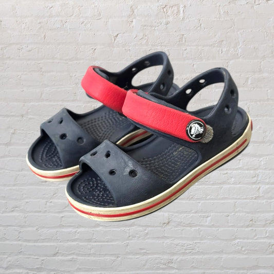 Navy blue kids sandals with red straps, featuring a sporty design and perforated details.