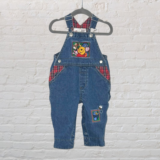 Denim overalls featuring Winnie the Pooh embroidery with red plaid accents and character patches.