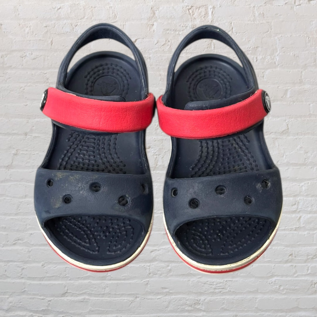 Navy blue kids sandals with red straps, featuring a sporty design and perforated details.