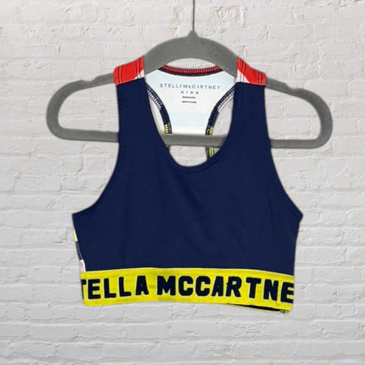 Navy blue sports bra for kids with red shoulder accents and yellow logo band by Stella McCartney Kids.