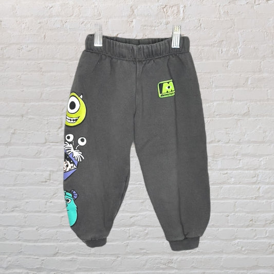 Dark grey fleece sweatpants with Monsters Inc. character graphics, featuring a green Monsters Inc. logo on the upper leg.