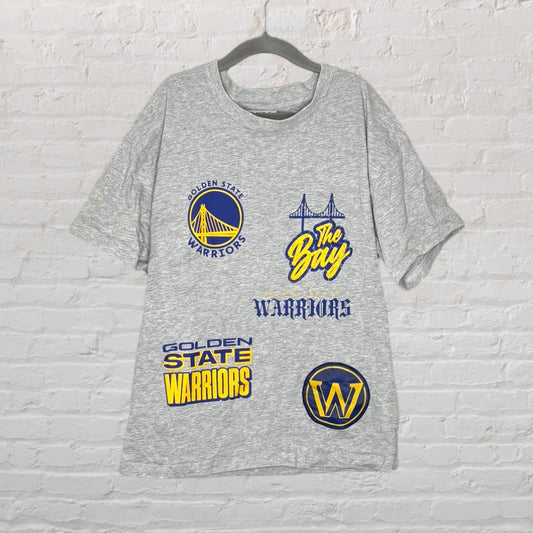 Grey Golden State Warriors T-shirt with multiple logos and graphics in blue and yellow, displayed on a hanger.