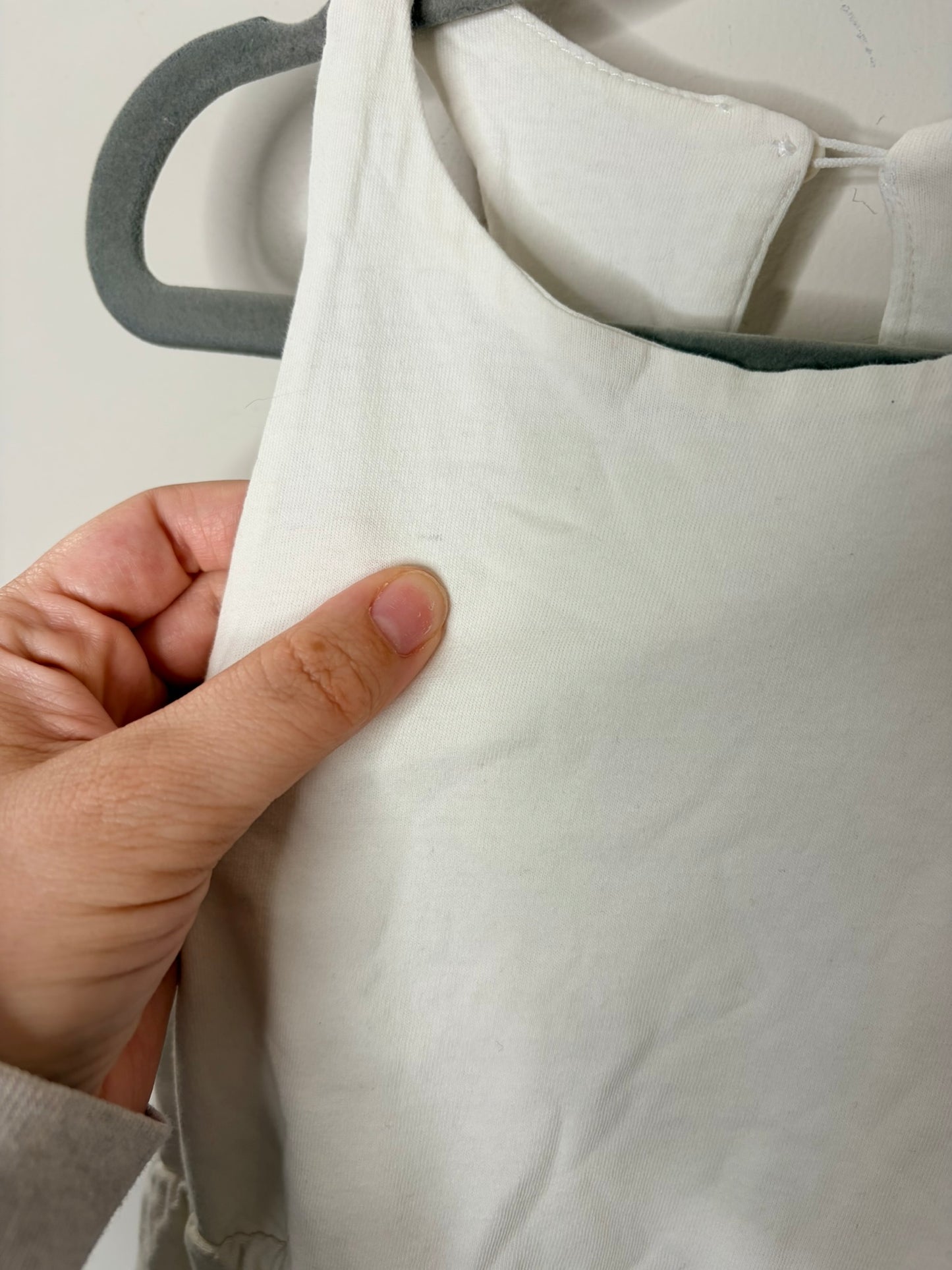 White sleeveless midi dress from Zara, displayed on a hanger against a white brick background.