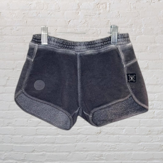 Washed black vintage-style shorts with elastic waistband and side patch detail, clipped on a hanger.
