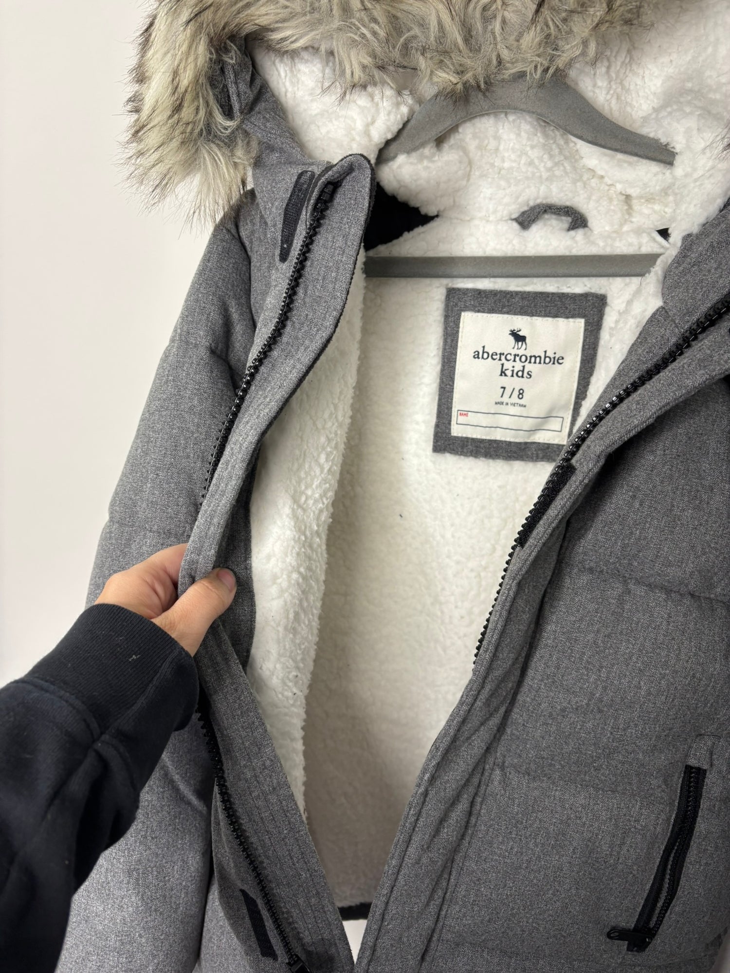 Grey padded puffer jacket with faux fur lined hood, displayed on a hanger.