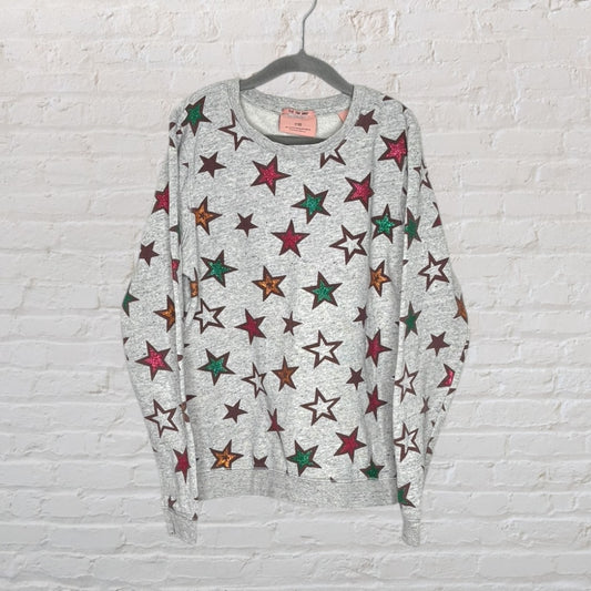 Grey sweatshirt with a colorful star print pattern in various colors including pink, green, and orange.