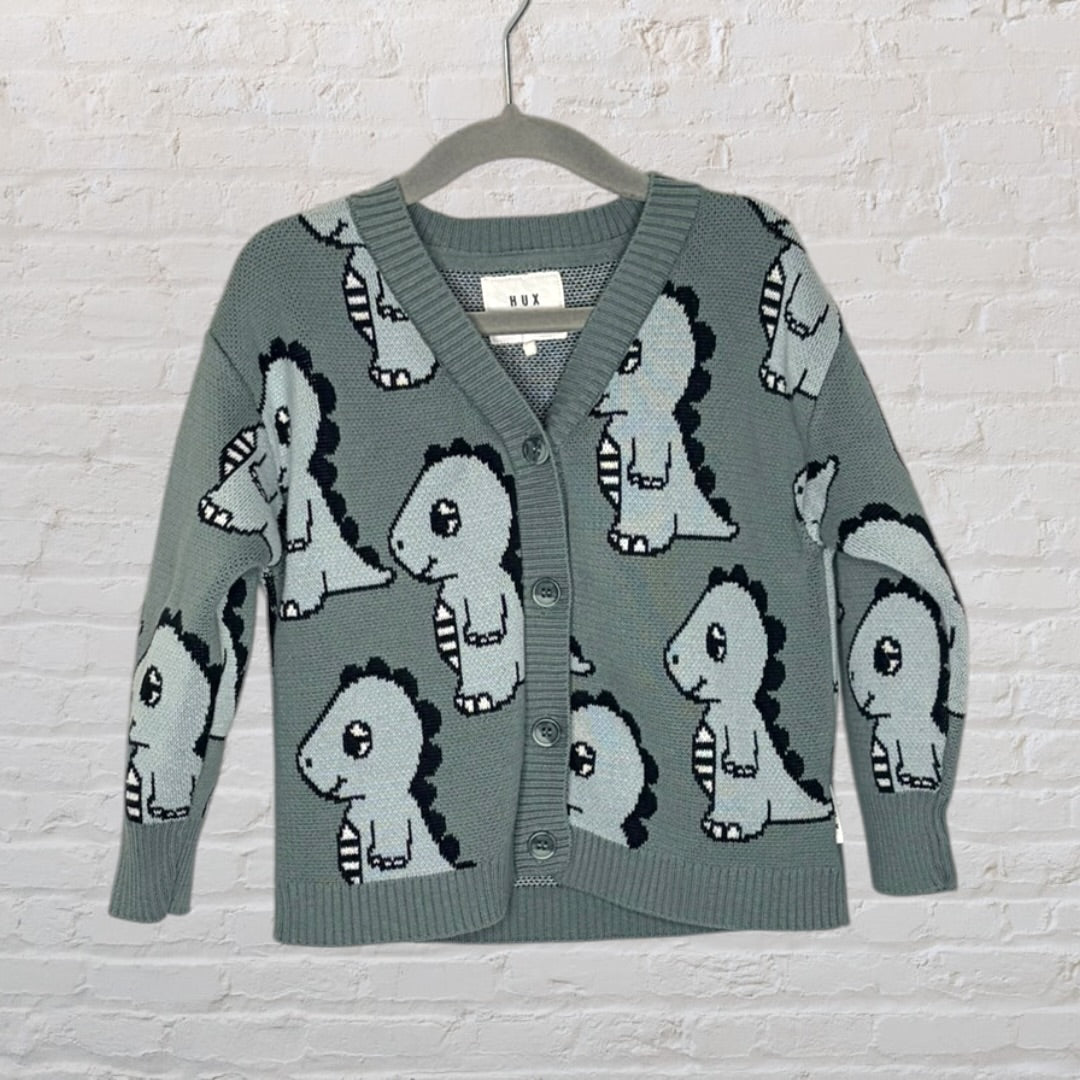 Gray cardigan with dinosaur print by Hux, featuring buttons down the front, hanging on a hanger.
