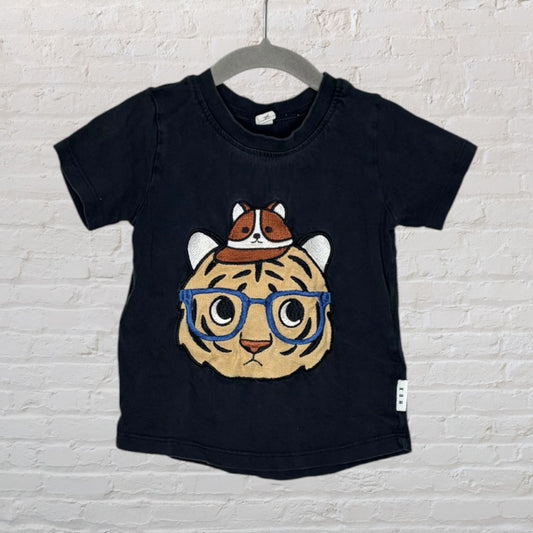 Black T-shirt featuring a cute embroidered tiger face with glasses and a small animal on top.